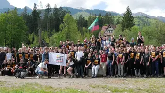 Grupa osób na polanie w tle las i choinki